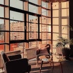 Sunlit modern office lounge with a city view, featuring elegant furniture and large windows in Berlin.